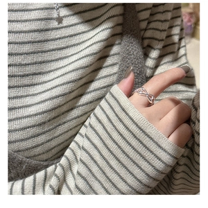 Close-up of minimalist S925 sterling silver hollow ring worn on hand with cozy knitwear