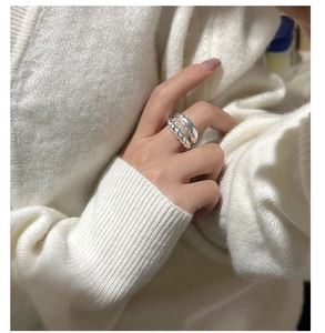 Detail view of silver S925 layered twist ring on model wearing white knitwear