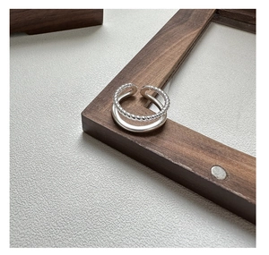 Detailed view of S925 silver double-layered twist ring on a wooden frame edge