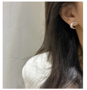 Gros plan de boucles d'oreilles lune minimalistes en argent sterling S925 sur un modèle
