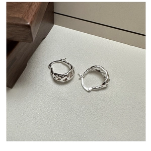 Dettaglio del marchio S925 su orecchini a cerchio in argento con texture irregolare