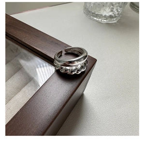 Macro shot of S925 sterling silver twist croissant open ring on a wooden box