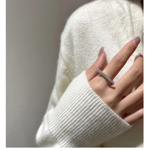 Close-up of minimalist S925 silver horizontal bar ring worn with a white knit sweater
