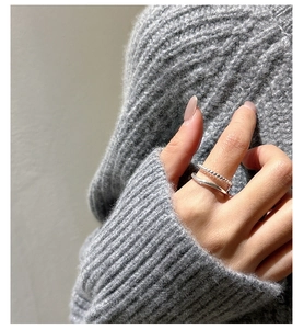 Close-up of double-layer silver twisted ring worn on hand with knit sweater detail
