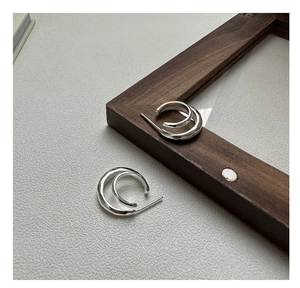 Detail of S925 sterling silver double-layer curved earrings on textured background