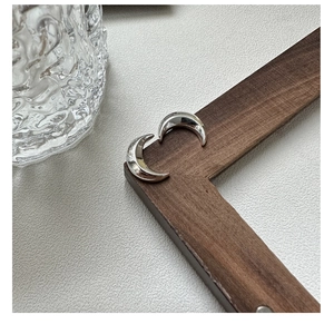 Gros plan de boucles d'oreilles lune en argent S925 sur un cadre en bois sombre