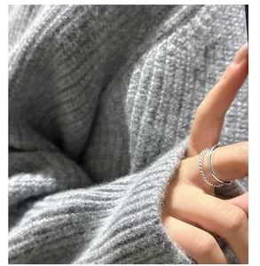 Close-up of minimalist double-layer silver twisted ring on model wearing a knit sweater