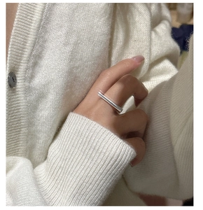 Minimalist S925 silver linear ring detail on hand with cozy beige knit background