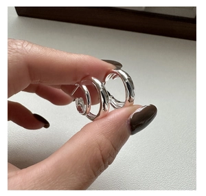 Three sizes of silver curved double-layered C-shaped hoop earrings held in hand