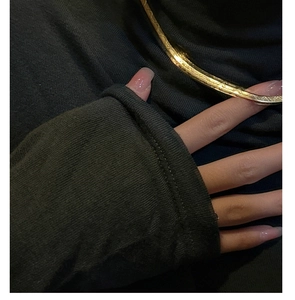 Detailed view of a gold-plated herringbone snake chain necklace on a gray turtleneck