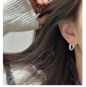Detailed close-up of chunky silver layered C-shape hoop earrings worn by a model