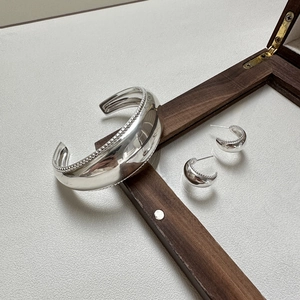 Polished S925 sterling silver curved jewelry set with beaded edges on a white background