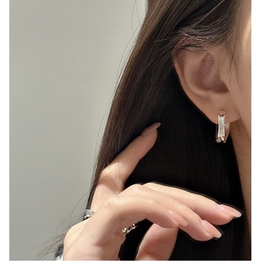 Close-up of minimalist S925 sterling silver curved earrings and irregular wavy ring on model