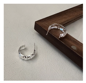 Vue macro des boucles d'oreilles en argent S925 en forme de C avec texture martelée
