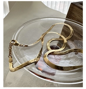 Close-up of golden flat herringbone chain with laser-engraved wavy texture and lobster clasp