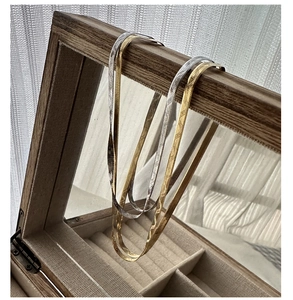 Detail of silver and gold herringbone snake chains on a vintage wooden jewelry box