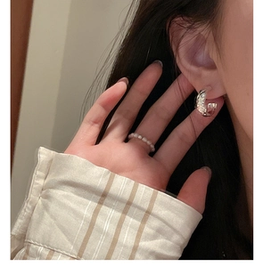 Vue détaillée des créoles argentées texture lave et d'une bague délicate en perles blanches