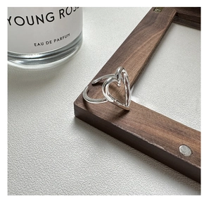 Detail of an S925 sterling silver hollow heart ring on a dark wooden frame background