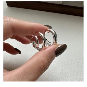 Detailed close-up of small silver S925 hoop earrings with minimalist organic wave texture