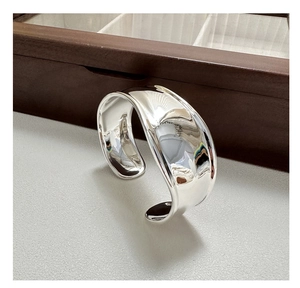 Close-up of minimalist polished silver wide cuff bracelet with smooth mirror finish