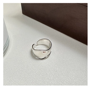 Detailed view of an irregular wide-band silver ring with a polished glossy finish