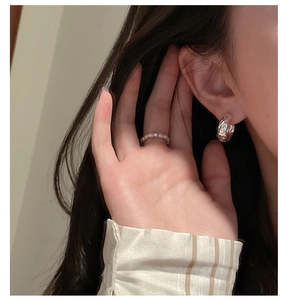 Gros plan d'une boucle d'oreille en argent texturé et bague perlée avec diamant sur modèle
