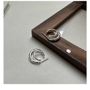 Close-up of S925 sterling silver double-layered curved hoop earrings with polished finish