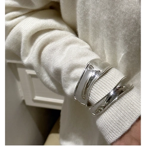 Close-up of polished S925 sterling silver wide curved cuff bracelet over a white knit sleeve