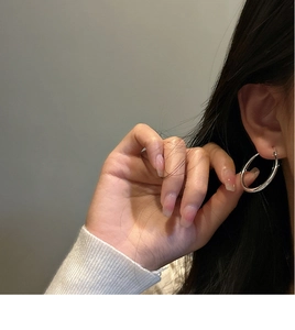 Close-up of minimalist S925 sterling silver hoop earrings worn by a model in warm light