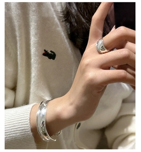 Polished silver wave ring and matching curved bangle set shown on model's hand