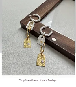 Macro detail of S925 sterling silver tag earrings with vintage scrollwork and bicolor finish