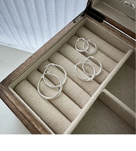 Detailed view of three sizes of polished S925 sterling silver hoop earrings in a wooden box