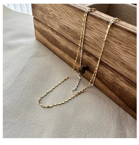 Detail of a two-tone gold and silver layered necklace with geometric rectangular links