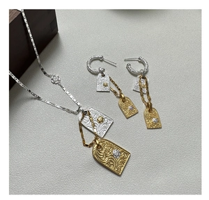Detail view of S925 silver necklace and earrings set with two-tone floral engraving