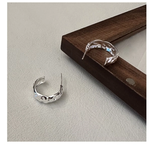 Détail des boucles d'oreilles en argent S925 avec texture de lave et finition brillante