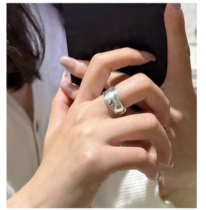 Close-up of a wide curved S925 silver ring with a polished mirror finish on a hand