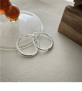 Macro shot of polished S925 sterling silver hoop earrings with clear hallmark stamp