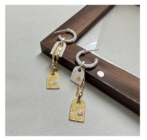 Macro shot of S925 silver retro earrings with two-tone floral engraving and zircon