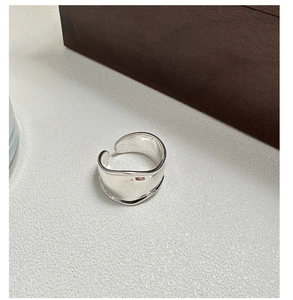 Macro view of wide minimalist silver-toned ring with fluid irregular curved design