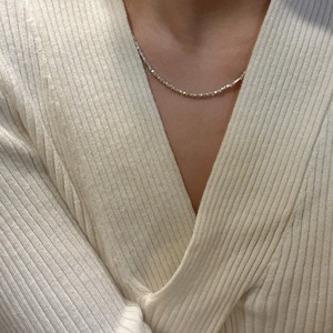 Gros plan d'un collier délicat en argent sterling sur un mannequin en tricot beige