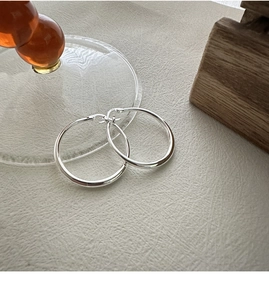 Macro shot of polished S925 sterling silver hoop earrings with 925 hallmark on grey background