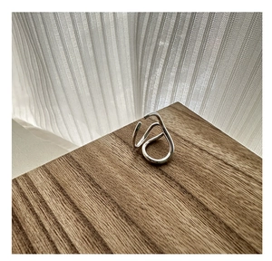 Macro detail of silver S925 minimalist wave ring on a textured brown wooden stand