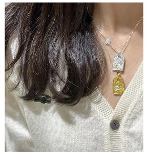 Macro shot of two-tone vintage pendant necklace featuring ornate scrollwork on model