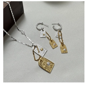Macro view of two-tone S925 silver earrings and necklace with engraved floral motifs