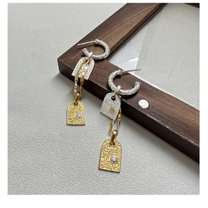 Macro detail of S925 silver vintage earrings featuring embossed floral pattern charms