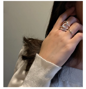 Silberner geknoteter Mehrschicht-Ring am Zeigefinger mit einem Strickpullover kombiniert