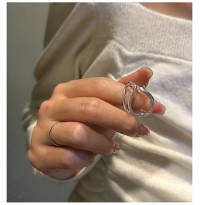 Detail shot of minimalist S925 silver irregular layered rings on a textured fabric