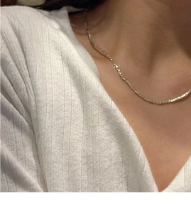 Gros plan d'un collier en argent S925 style pierre concassée porté sur un tricot