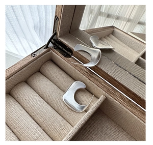 Detail of S925 sterling silver stamp on matte C-shaped earrings inside a jewelry box