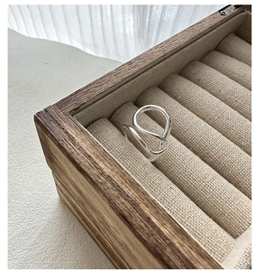 Macro shot of minimalist silver irregular flowing line ring on a premium jewelry box